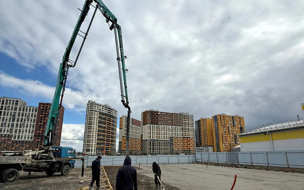 Автобетононасос с развёрнутой стрелой на крупной городской площадке